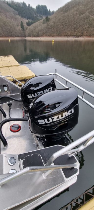 Zwei schwarze Außenbordmotoren auf einem Boot an einem ruhigen Gewässer.