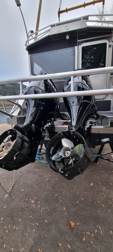 Zwei Außenbordmotoren an einem Boot, neben einer steinernen Uferkante.