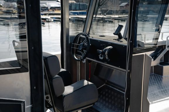 Innenansicht eines Boatsteuers mit Schreibtisch, Sitzen und Blick auf einen Hafen.